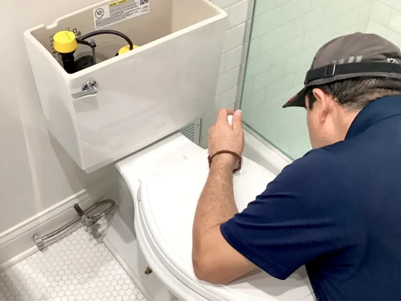 Plumber repairing a toilet in a Wildomar, CA bathroom